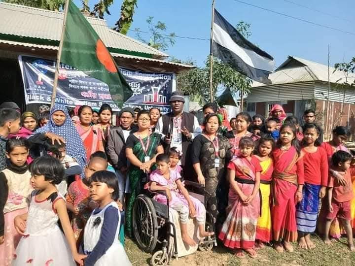 Mothers, children and a wheelchair user gathered beneath Bangladesh and Foundation flags